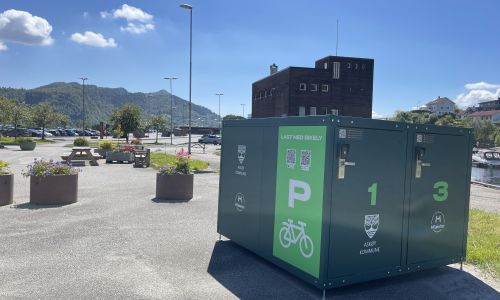 En grønn boks på en parkeringsplass, boksen er stor nok til å inneholde fire sykler