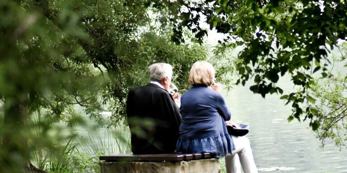 En eldre mann og en eldre kvinne som sitter på en benk under et tre