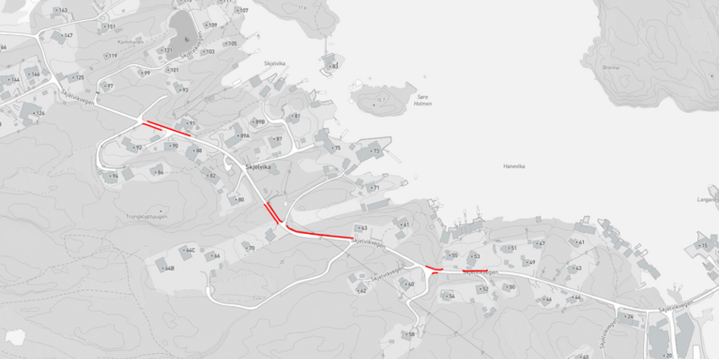 Kart over Skjelvika-området som viser veier og bebyggelse. Skjelvikvegen er markert med røde streker på kartet, noe som indikerer hvor veiarbeidet skal foregå. Kartet viser flere veier, hus og andre bygninger i området rundt Skjelvika.